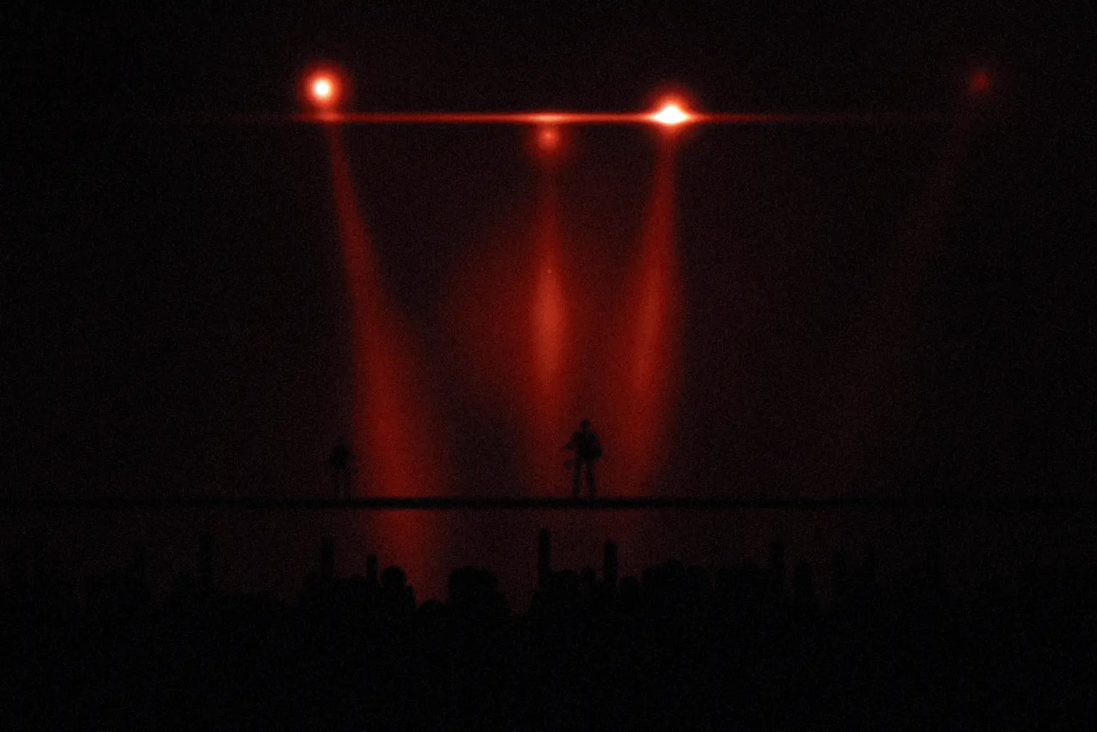 The band mid-set, lit from behind by a bank of white lights.
